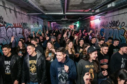 Dancefloor animé d'une boite électro souterraine à Paris avec une foule de jeunes adultes dansant sous des néons UV sur fond de murs en béton brut