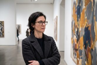 Femme portant des lunettes en écaille devant une peinture abstraite dans un musée d'art contemporain en hiver