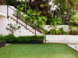 Gazon synthétique : les secrets d’une pose réussie pour un jardin parfait a white house with a green lawn and stairs